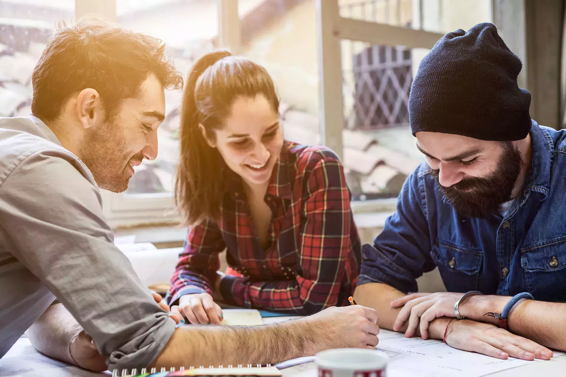 Drei Studenten arbeiten gemeinsam und lachen. 