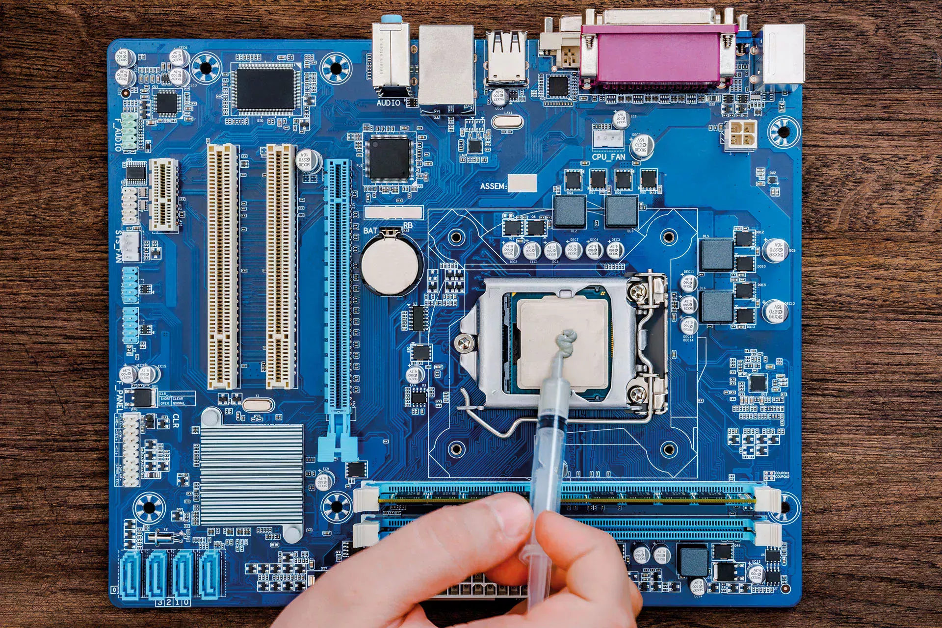 Wärmeleitpaste wird auf den CPU Sockel eines Motherboards aufgetragen